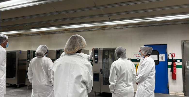 Photo de personnes en blouse visitant la cuisine centrale